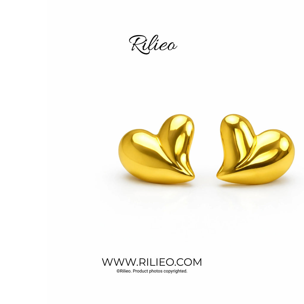 Pair of gold plated heart stud earrings on white background, modern jewelry