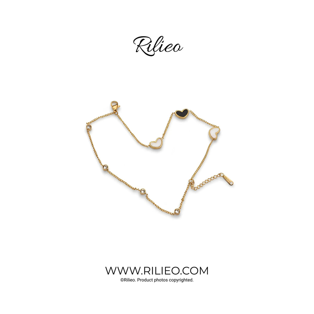 Gold plated heart charm bracelet with delicate chain and cubic zirconia accents on white background