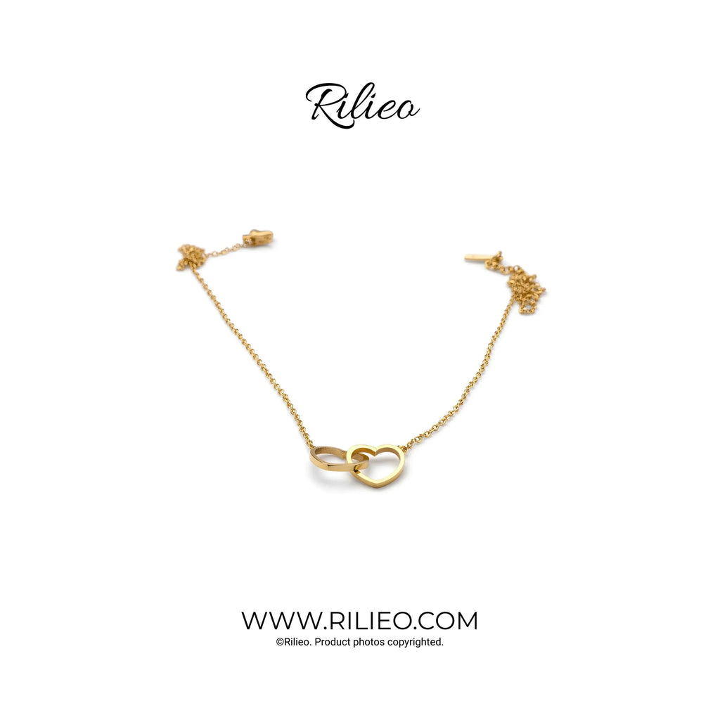Gold plated chain bracelet with interlocking heart and ring charms on white background