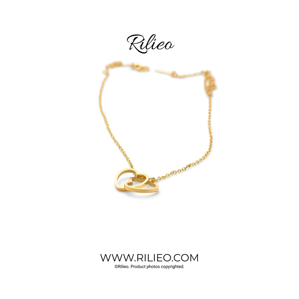 Gold plated necklace with two interlocking heart pendants on a fine chain, minimal style