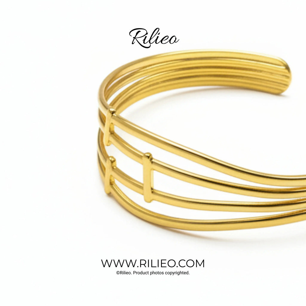 Modern gold plated cuff bracelet with three parallel bands on white background